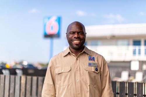 a man is smiling while standing in front of a fence at Motel 6-Gardena, CA - South in Gardena