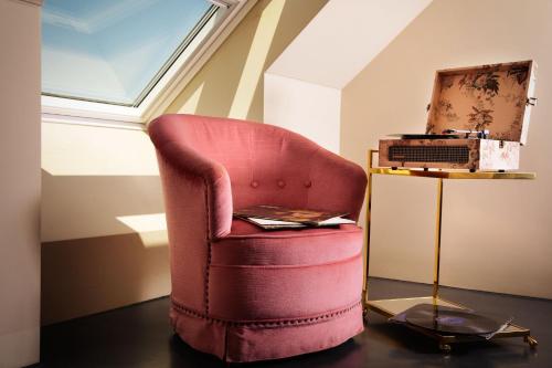 a red chair sitting in the corner of a room at Design-Hotel JAMS in Munich