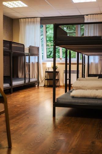 a room with three bunk beds and a wooden floor at Villa14 - Noisy Party Hostel in Pärnu