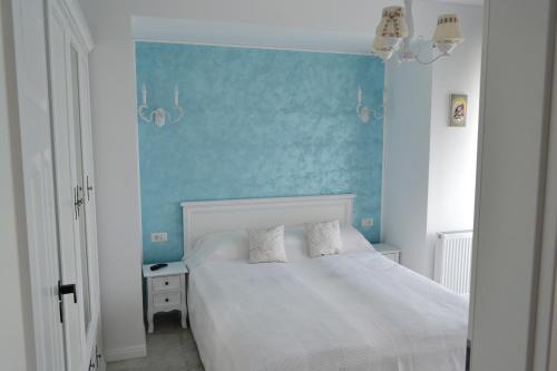a bedroom with a white bed and a blue wall at Apartament POK in Constanţa