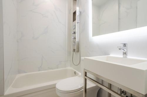 a white bathroom with a sink and a toilet at Olympia Hotel by Lodgo in Montréal