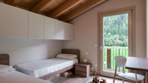 two beds in a room with a large window at Olgas Chalet in Vione