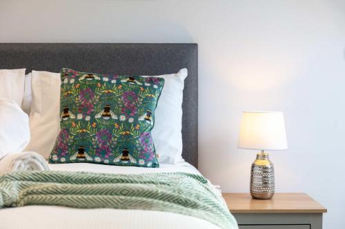 a bed with a green pillow and a table with a lamp at No20 Mansfield - Donnini Apartments in Prestwick