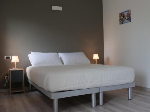 a bed with white sheets and pillows and two lamps at Casa Villaggio Laguna in Venice