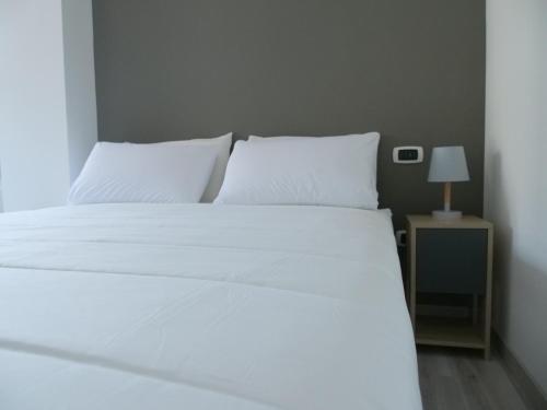 a bed with white sheets and a nightstand with a lamp at Casa Villaggio Laguna in Venice