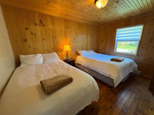 1 Schlafzimmer mit 2 Betten in einer Holzhütte in der Unterkunft Lanes Riverhouse Inn & Cottages in Montague