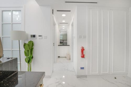 a white hallway with a red fire extinguisher on the wall at EasyGo- Luxury Living with Resort Facilities and Amenities in Dubai