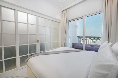 a bedroom with a white bed and a large window at EasyGo- Luxury Living with Resort Facilities and Amenities in Dubai