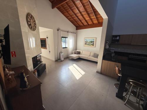 a large living room with a clock on the wall at Casa Alto da Serra in Serra Negra