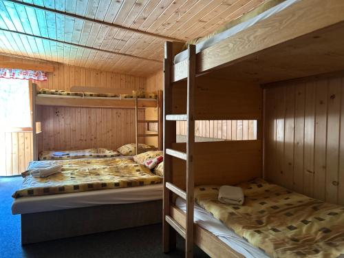 two bunk beds in a room with wooden walls at Chata SKI Jezersko in Jezersko