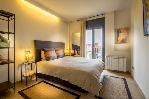 1 dormitorio con cama grande y ventana grande en Can Tarongeta Apartments, en Palafrugell
