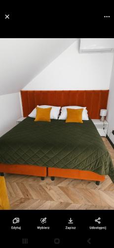 a bed with a green comforter and yellow pillows at Noclegi Beskidzkie Stodoły in Odrzechowa