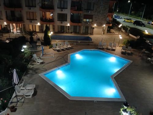 a large swimming pool in a courtyard at night at Апартамент Бриз 16 in Sunny Beach