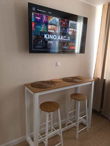 a tv hanging on a wall above a bar with two stools at Super Central Studio with palace view! in Warsaw