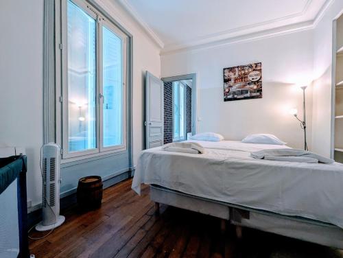 une chambre avec un lit et une grande fenêtre dans l'établissement Chic apart avec parking tout près de Paris, à Saint-Denis