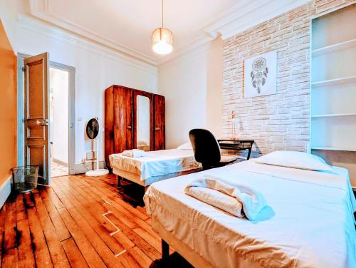 une chambre avec deux lits et un mur de briques dans l'établissement Chic apart avec parking tout près de Paris, à Saint-Denis