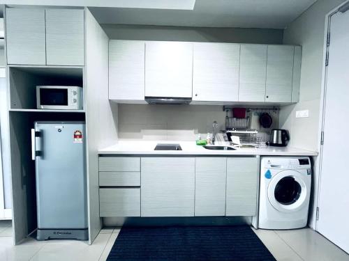 a kitchen with white cabinets and a washing machine at Aurora Homes at i-City - WiFi TV Box and 1 Carpark in Shah Alam