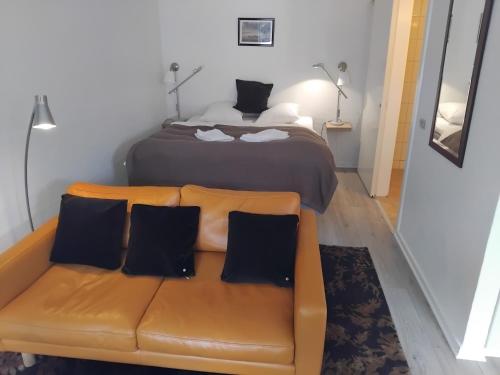 a bedroom with a bed and a brown couch with pillows at Hotel Strandvejen in Fanø