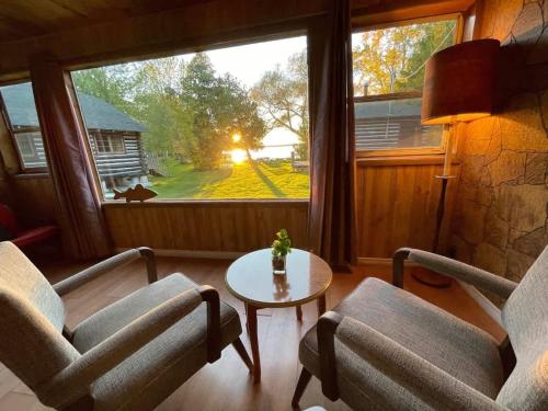 sala de estar con 2 sillas, mesa y ventana en Balsam Lake - 2-Bedroom Cottage #8, en Kawartha Lakes
