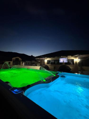 a swimming pool with green illumination at night at El Ryo 2 in Călimăneşti