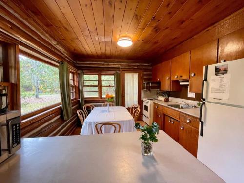 Una cocina con una mesa y un refrigerador blanco. en 3-Bedroom Cottage on Balsam Lake in Kawarthas #14, en Kawartha Lakes