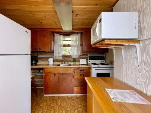 Una cocina con gabinetes de madera y un refrigerador blanco. en 1-Bedroom Balsam Lake Cottage #9, en Kawartha Lakes