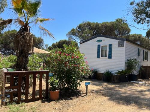 a white house with a palm tree and a fence at Bungalow vue mer Pampelonne St-Tropez in Saint-Tropez