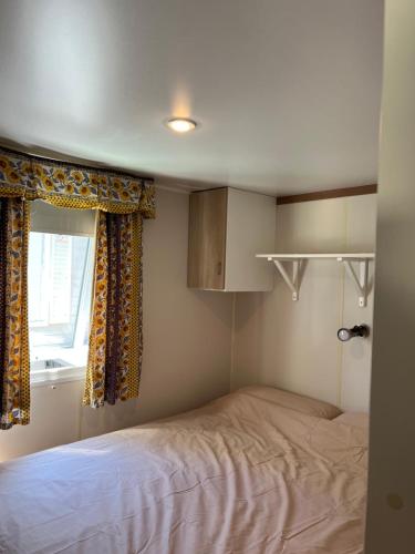 a small bedroom with a bed and a window at Bungalow vue mer Pampelonne St-Tropez in Saint-Tropez