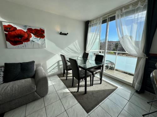 un salon avec une table, des chaises et un canapé dans l'établissement Appartement Port Marianne Montpellier, à Montpellier
