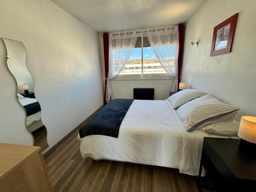 une chambre avec un grand lit et une fenêtre dans l'établissement Appartement Port Marianne Montpellier, à Montpellier