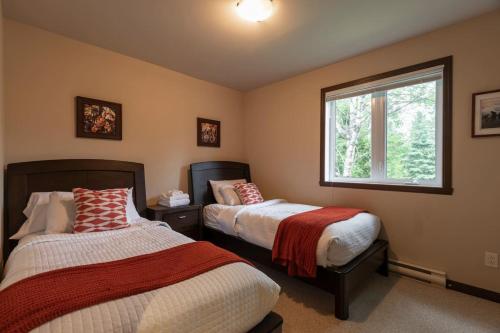 a bedroom with two beds and a window at Piscine - Golf - Velo INOUT - Espace Jeux - Navette in Mont-Tremblant