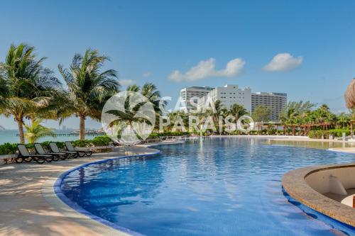 een zwembad op een resort met palmbomen bij BLUE DREAM Beachfront 2 BDR by Casa Paraiso in Cancun