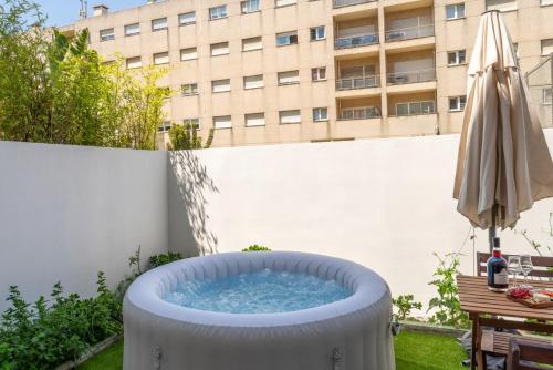 a hot tub on a patio with an umbrella at HostWise – Modern Flat w/ Terrace | Near the Beach in Matosinhos