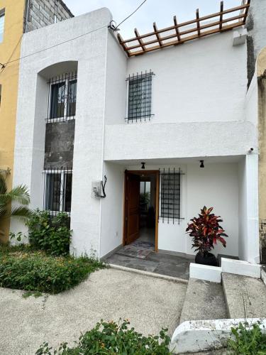 a white house with a door and a window at Casa familiar para estrenar! 10 mins de la playa in Manta