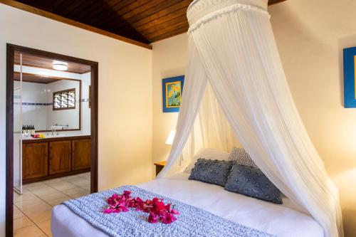 ein Schlafzimmer mit einem Himmelbett mit rosa Blumen drauf in der Unterkunft Poppy's on the Lagoon in Port Vila
