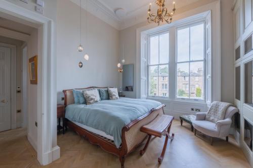 Un dormitorio con una cama y una silla y una ventana. en Luxury West End flat with stunning bay window views, en Edimburgo
