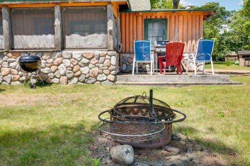 a grill in front of a house with chairs and a table at South Twin Lake Cabin with Seasonal Dock and Slip! in Conover