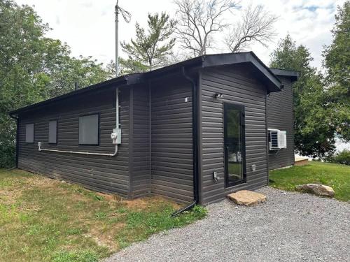 a black tiny house in a yard at 3-bedroom Lakefront Villa #10 in Lakefield
