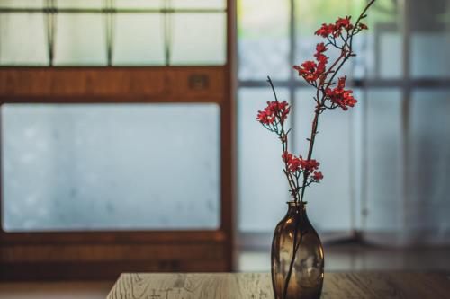 a vase with red flowers in it sitting on a table at サウナとアートの宿 瀬戸内一棟貸切 Sei-Jima Retreat in Sakaide