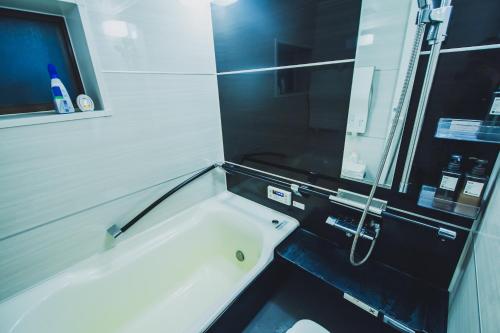 a bathroom with a white tub and a mirror at サウナとアートの宿 瀬戸内一棟貸切 Sei-Jima Retreat in Sakaide