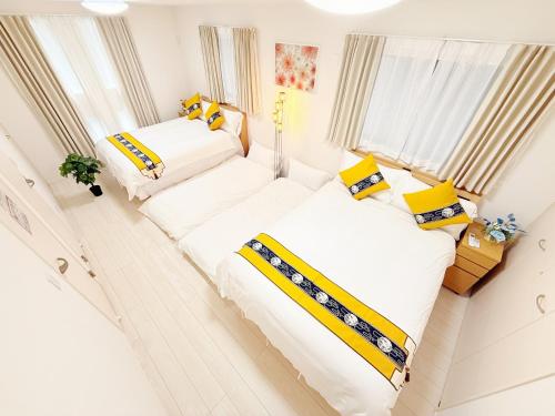 two beds in a room with white and yellow pillows at 吉屋2号館 in Tokyo