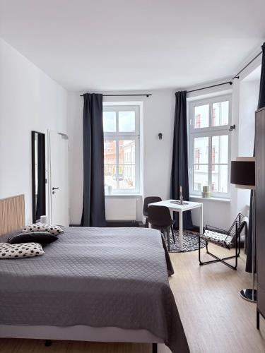 a bedroom with a bed and a table and two windows at Studios am Kniepertor in Stralsund