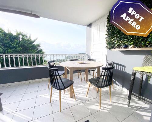un patio con tavolo e sedie su un balcone di F3 Famille ou Amis - Piscine, Vue Mer et Calme - Anse à l'Âne, 3-Îlets a Les Trois-Îlets