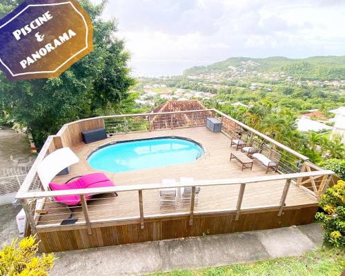una piscina su una terrazza in legno con sedie e ombrellone di F3 Famille ou Amis - Piscine, Vue Mer et Calme - Anse à l'Âne, 3-Îlets a Les Trois-Îlets