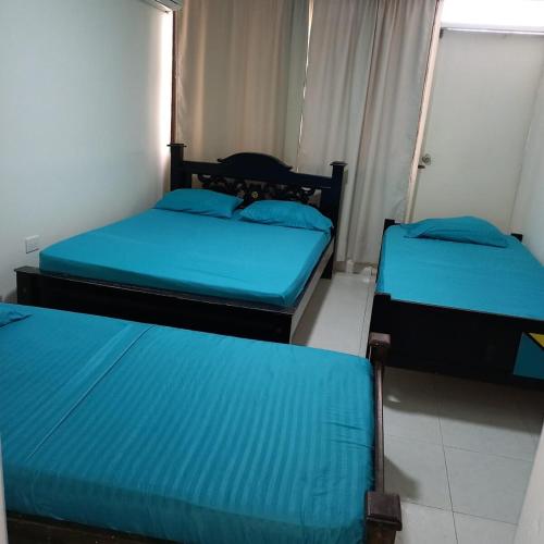 three beds in a room with blue sheets at Puesta del sol in Rodadero