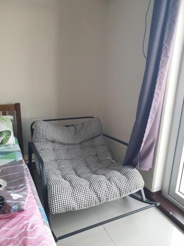 a chair sitting next to a bed in a room at Studio Condo at Saekyung Looc in Lo-oc