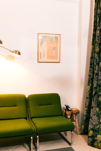 a green couch in a room with a picture on the wall at Hotel du Temps Madrid in Madrid