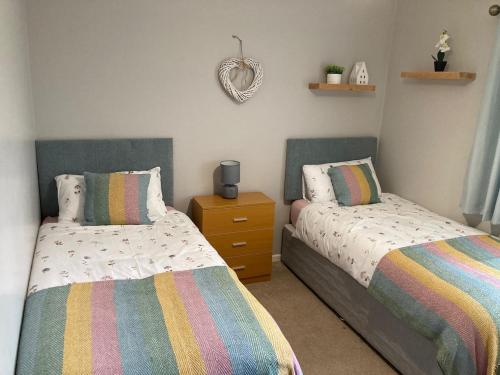 a bedroom with two beds and a dresser and a mirror at Forest Cottage in Newcastle