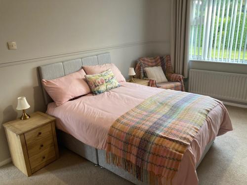 a bedroom with a bed with pink pillows and a chair at Forest Cottage in Newcastle
