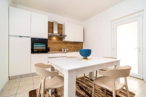 a white kitchen with a white table and chairs at Villademar lunarossa in Marzamemi